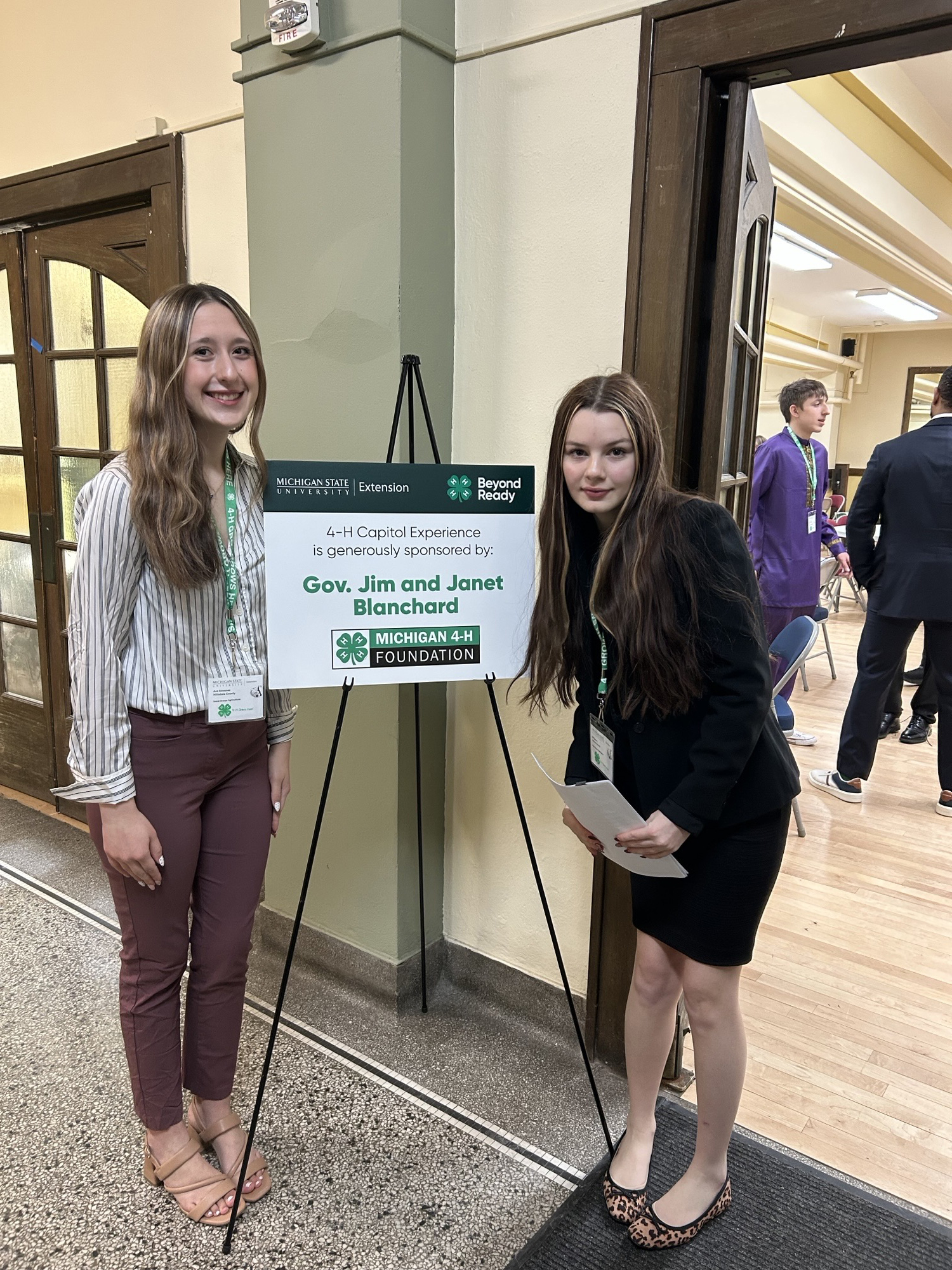 Two youth next to a sign that says "4-H Capitol Experience is generously sponsored by Gov. Jim and Janet Blanchard.